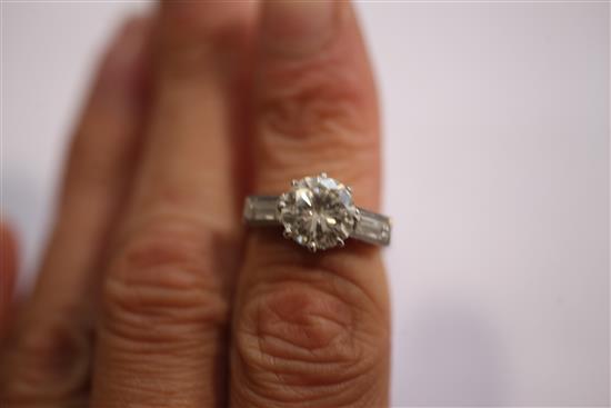 An early to mid 20th century platinum and single stone diamond ring with baguette cut diamond set shoulders, size I.